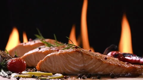 Grilled salmon fish with various vegetables on the flaming grill Vidéo 145385936