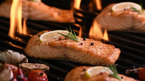 Grilled salmon fish with various vegetables on the flaming grill Vidéo 145386021
