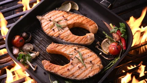 Grilled salmon fish with various vegetables on pan on the flaming grill Video stock 145386108