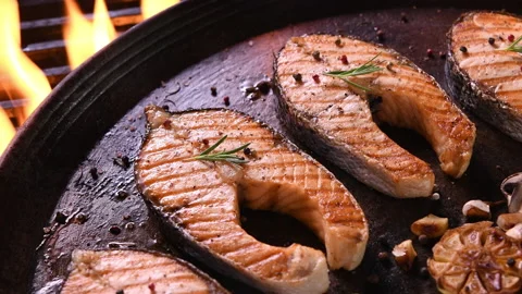 Grilled salmon fish with various vegetables on pan on the flaming grill Видео 146826871