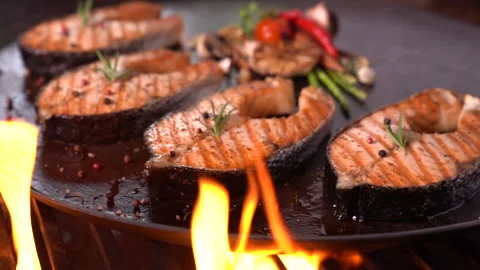 Grilled salmon fish with various vegetables on pan on the flaming grill Vidéo 147239378