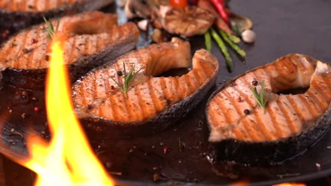 Grilled salmon fish with various vegetables on pan on the flaming grill Vidéo 148792050