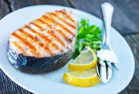 Grilled salmon steak with lemon on white plate Stock Photos