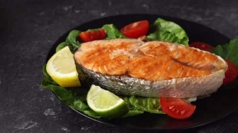 Grilled salmon steak with salad leaves in ablack plate Stock Footage 138381053