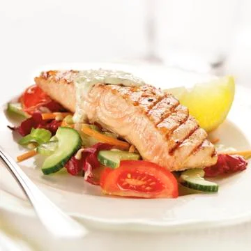 Grilled salmon steak served on letuce tomato and cucumber Stock Photos