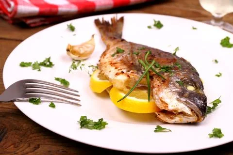 Grilled sea bream fish, lemon on white plate Stock Photos