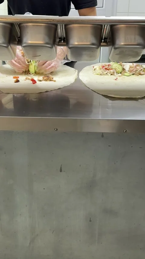 Grilled Shawarma Meat Added over Fresh Vegetables on Flatbread by Gloved Cook Stock Footage 345172564