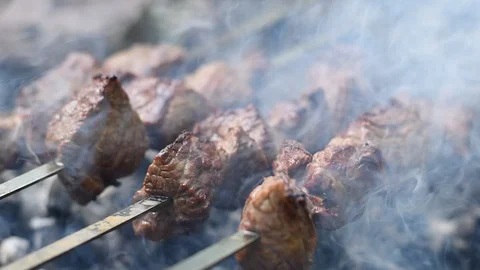 Grilled shish kebab. Slow motion a man's hands rotating shashlik on the skewe Stock Footage 112717997