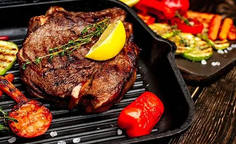 Grilled steak with lemon slice and vegetables on a grill Stock Photos