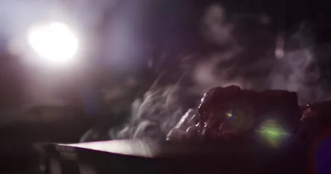 Grilled Steak Resting and Steaming on Wooden Board, Backlit Barbecue Close Up Vídeo Stock 340321457