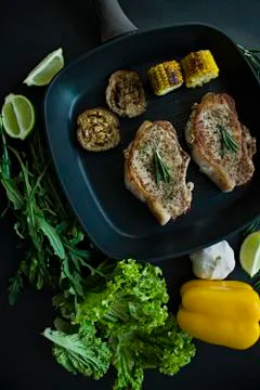 Grilled steak with vegetables in a pan decorated with rosemary. Fresh greens. Stock Photos