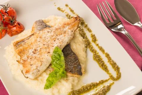 Grilled trout with risotto, tomatoes, and pesto Stock Photos