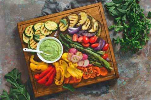 Grilled vegetables on a rustic background, served on a wooden board with avoc Stock Photos