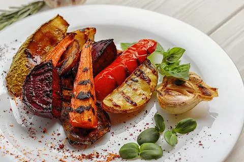 Grilled vegetables on a white plate, on a white background Stock Photos