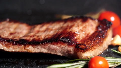 Grilling beef steak, meat steak with rosemary, tomatoes, garlic on iron plate Stock Footage 222775347