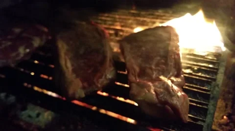 Grilling black angus t-bone steaks, on a charcoal bargeque, at a restaurant k Stock Footage 58632030