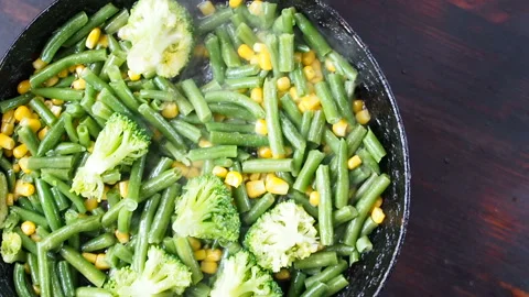Grilling broccoli in a cast iron pan with beans and corn. slow motion Vídeos de archivo 104272268