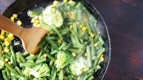 Grilling broccoli in a cast iron pan with beans and corn. slow motion Video stock 104272700