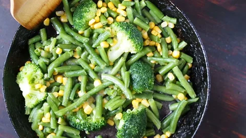 Grilling broccoli in a cast iron pan with beans and corn. slow motion Stock Footage 104273148