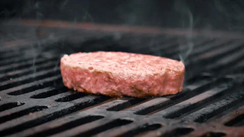 Grilling a burger cutlet. Camera movement over the barbecue grill. Stock Footage 135386804