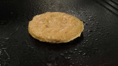 Grilling chicken burger cutlet on the frying surface, camera moves closer Stock Footage 76897702