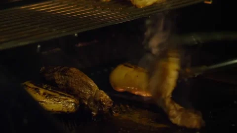 Grilling chicken over open flame in dark barbecue setting. image Stock Footage 276178392