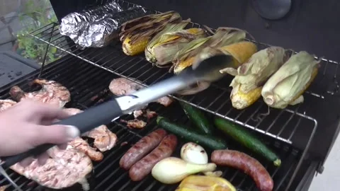 Grilling corn on the cob, vegetables, fish, chicken, &amp; sausage on a BBQ grill. Stock Footage 141836622