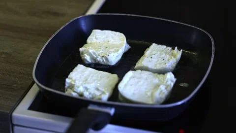 Grilling halloumi on a heated pan creates golden grill marks, light smoke, an Stock Footage 322196475
