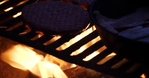 Grilling hamburger and bacon over open fire camping close up Stock Footage 171180783