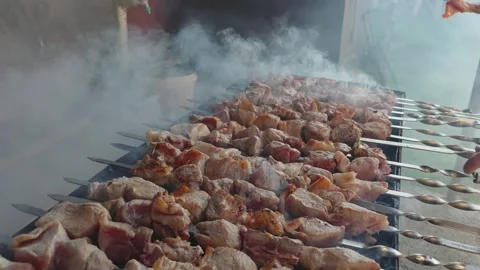 Grilling marinated meat skewers over hot coals with smoke rising Stock Footage 341892499
