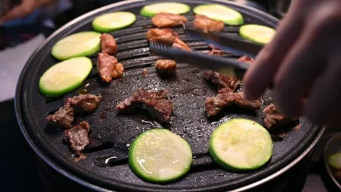 Grilling Meat and Vegetables on a Hot Plate with Tongs in a Restaurant Settin Vidéo 337696214