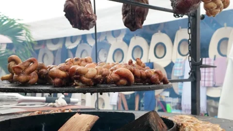 Grilling meat at circular barbecue dinner party in street food market outside - Stock Footage 335186167