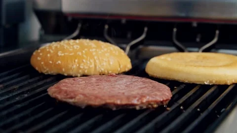 Grilling meat cutlet and burger buns. Frying raw cutlet and bread for hamburger Stock Footage 158644574