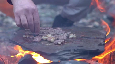 Grilling Meat on Fire-Heated Rock – Bushcraft Outdoor Cooking Video stock 303661659