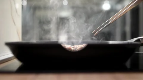 Grilling meat on a grill pan. Smoking sausages are turned over with tongs. Stock Footage 244334998