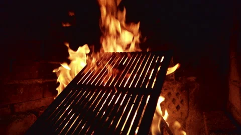 Grilling at night with flames rising from the grill in a backyard setting in Stock Footage 344320039