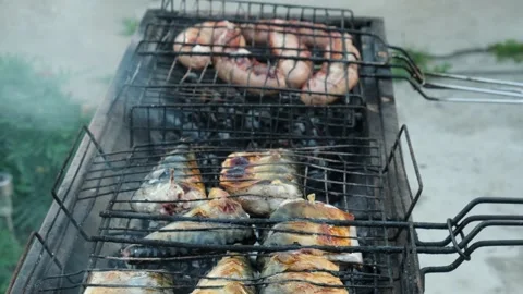 Grilling pieces of fish and meat sausages on charcoal, close-up. Stock Footage 201712838