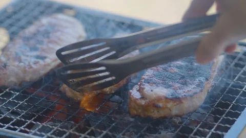 Grilling pork meat being roasted on a grill Stock Footage 114368996