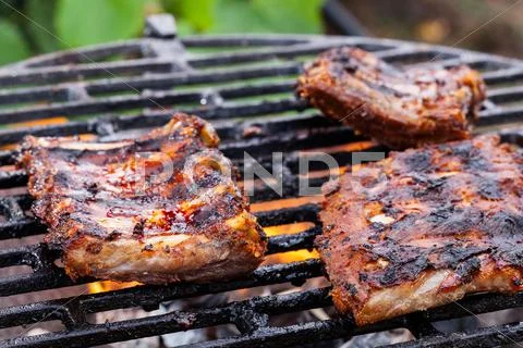 Grilling pork spareribs on barbecue grill. selective focus Stock Photos