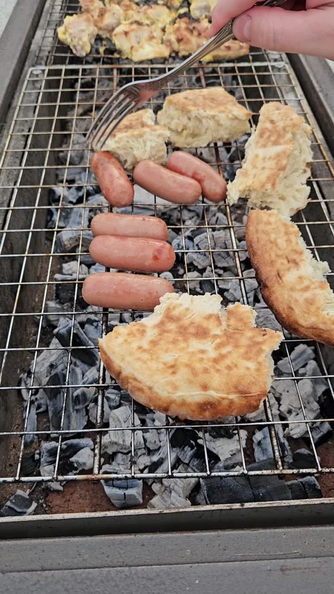 Grilling sausages, flatbread, and marinated meat over hot charcoal Stock Footage 308823778