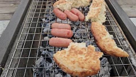 Grilling sausages, flatbread, and marinated meat over hot charcoal Stock Footage 308823779