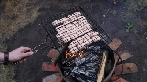 Grilling sausages over an open fire pit with glowing embers and smoke Stock Footage 337105332