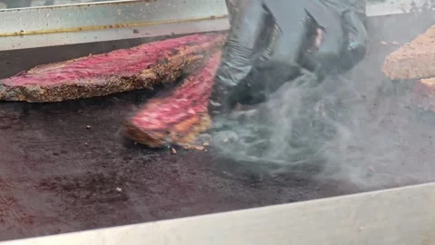 Grilling steak on a flat top for a tasty cooking experience Stock Footage 339595144