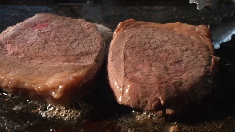 Grilling steaks on BBQ close up. Cooking beef on barbecue using tongs to flip Video stock 115778428
