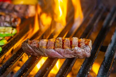 Grilling steaks on flaming grill and shot with selective focus Stock Photos