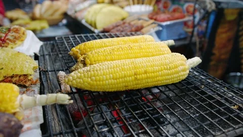 Grilling sweet corn on the cob over hot coals at a night market, Vietnam Stock-Footage 336982390