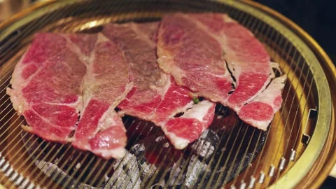 Grilling thin slices of Beef on a charcoal barbecue in an indoor restaurant Vídeo Stock 324573632