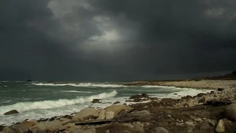 Grim dark grey stormy clouds at the ocean. Rocky coast and shore. Stock Footage 99156962
