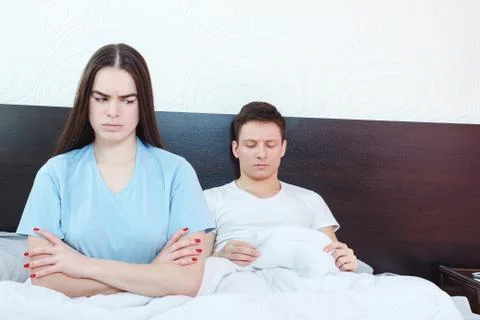 Grim dejected and emotionally hurt  woman is angry while man in background st Stock Photos