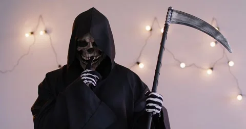 Grim reaper in cloak standing with scythe, putting skeletal finger to lips Stock Footage 312096593